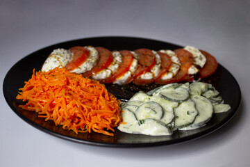 Vegetable platter; with Caprese salad, with tomato and cheese, mozzarella Di Buffalo and basil; there is also shredded carrot salad, and cucumber salad, with vinaigrette cream with mint.