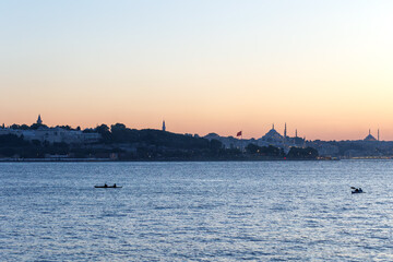 Tourists rowing in the Bosphorus at sunset historic peninsula at the background
