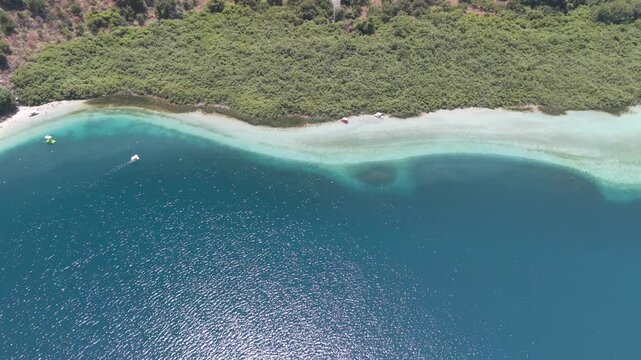 Fly with me above the Crete kournas lake during summer vacation phase with blue sky and sunshine while tourists use their paddle boat at the fresh sweet water lake