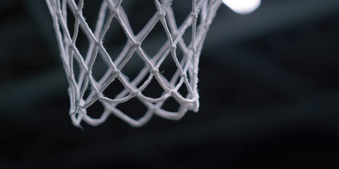 Close up of basketball net with frayed ends under dim lighting
