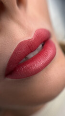 A close-up shot of a woman's lips as she applies a pink-tinted lip balm or lipstick. Her lips are...
