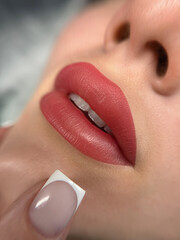 A close-up shot of a woman's lips as she applies a pink-tinted lip balm or lipstick. Her lips are...