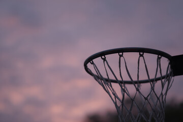 Basketball hoop silhouetted against nostalgic dusk sky
