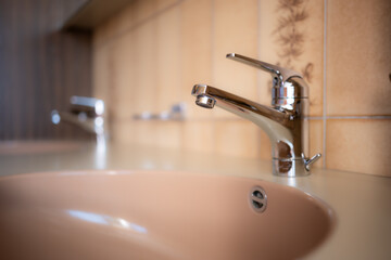 Shiny, chrome water tap inside apartment bathroom. Close up shot