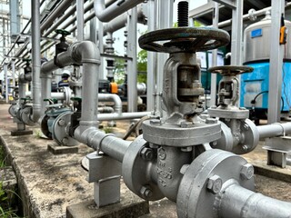 Close-up of stainless steel industrial piping system with valves and control components in a factory. Used in fluid transfer, process engineering, and manufacturing environments.