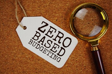 Zero Based Budgeting text on price tag with magnifying glass on cork board background