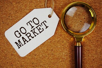 GTM abbreviation of Go To Market text on price tag with magnifying glass on cork board background