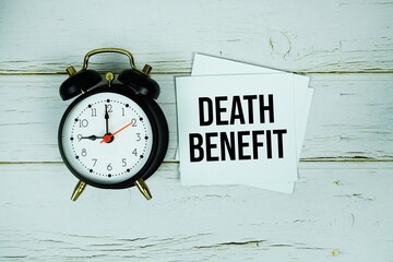 Death Benefit text message on paper with alarm clock on wooden background