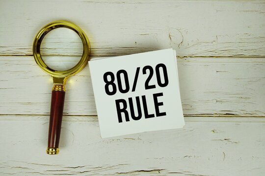 80/20 Rule text message on paper with magnifying glass on wooden background