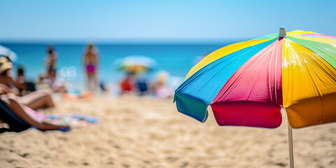 close up of a colorful beach umbrella with people relaxing by the sea on a summer day in background - summer vacation concept