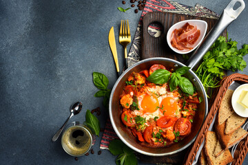 Shakshuka eggs in a pan with toast on a black concrete background. Poached eggs in a spicy tomato pepper sauce. Traditional Jewish breakfast. Healthy meal.