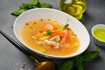 Seafood soup: salmon, sea bass with red caviar. In a white oval bowl. Close-up. Food rich in omega 3.