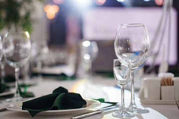 Setting the festive table. empty wine glasses and plates with green napkins.
