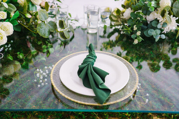 Setting the festive table. empty plates with green napkins. flower arrangement