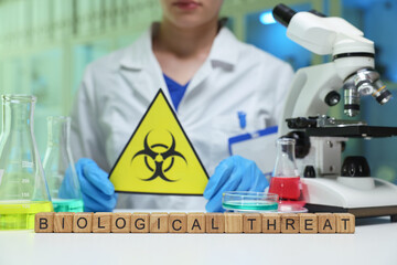 A researcher holds a biological hazard sign, emphasizing the importance of safety in lab...