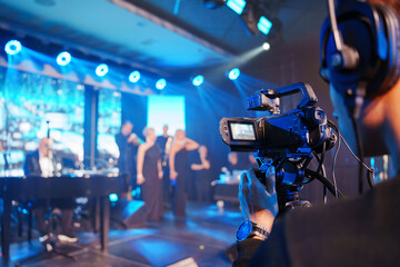 A professional videographer is filming a concert on stage. blurred stage.