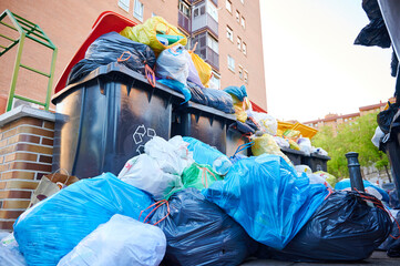 Trash bags pile up around street containers during a garbage collection strike, creating unsanitary...