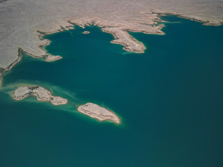 Isolated sandy islands in the blue Kuimazar Reservoir stand out against dry land. The aerial view...
