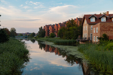 Fototapeta premium Residential building made of bricks on the shore of the reservoir