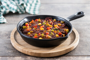 Mexican chilli beans with vegetables in iron pan on wooden table