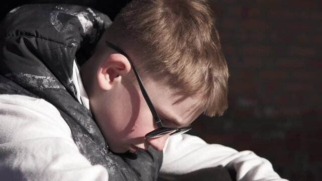 A teenager sits sadly in an abandoned building after being bullied at school. Childhood depression and migraine concept.