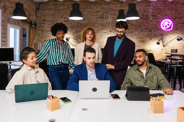 Marketing team working together on a project using laptop in the office