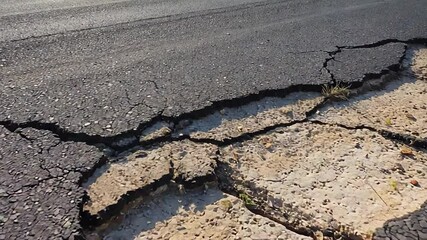 Damaged asphalt road showing cracks and deterioration