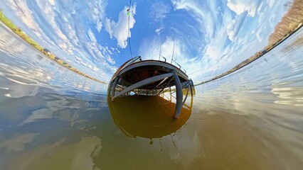 Surreal 360-degree perspective of a fishing pier over calm lake water under dramatic skies. Artistic and immersive spherical composition suitable for VR, environmental, or travel visual design