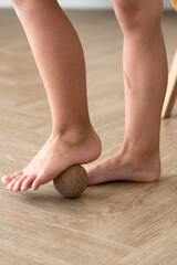 prevention of flat feet, close-up of child's feet with massage ball, orthopedic exercises