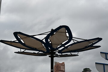 osłona przed słońcem w kształcie kwiatka w tle wysokie budynki © Miroslaw