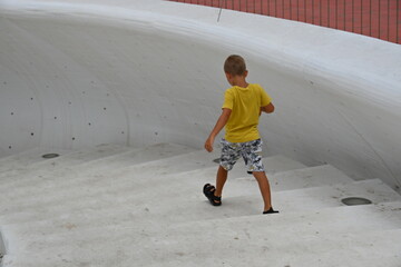 mały chłopiec w żółtej koszulce schodzi białymi schodami na plaże  © Miroslaw