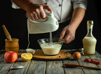 A person skillfully mixes a creamy batter in a bowl with an electric mixer, surrounded by fresh ingredients like apple, egg, and milk. The warm kitchen atmosphere enhances the culinary experience