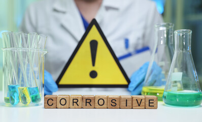 Cautionary sign highlighting corrosive substances alongside laboratory glassware and important...