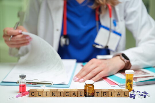 A healthcare professional reviewing documents related to a clinical trial with medications and vials.
