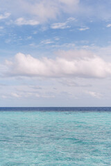 Tranquil view of the endless turquoise ocean meeting the sky at the horizon, captured on a calm tropical day. The simplicity of the scene evokes peace, serenity, and a timeless sense of escape.