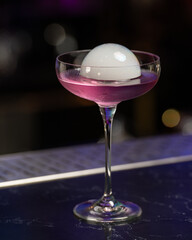 This visually striking pink alcoholic cocktail in a coupe glass features a large, dome-shaped smoke...