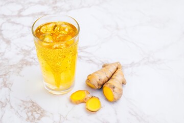 Golden Turmeric Ginger Tonic Served in a Glass With Fresh Roots Nearby