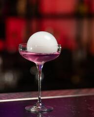 This visually striking pink alcoholic cocktail in a coupe glass features a large, dome-shaped smoke...