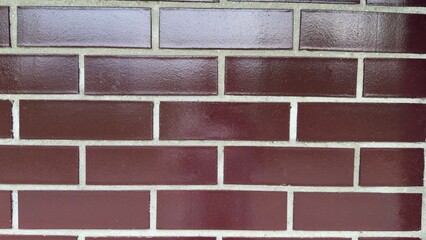 Decorative brown brick wall with glossy finish and light joints — modern texture for...