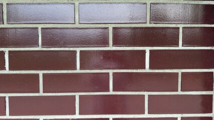 Decorative brown brick wall with glossy finish and light joints — modern texture for...