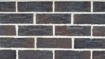 Dark brick wall with white mortar joints and embossed texture as architectural or design background