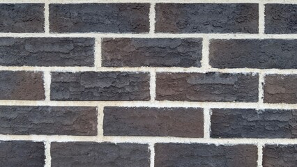 Dark brick wall with white mortar joints and embossed texture as architectural or design background