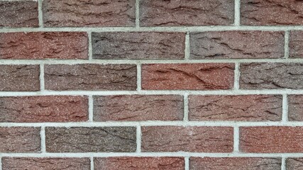 Red and brown brick wall with natural texture and uneven coloration — classic construction...