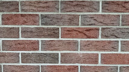 Red and brown brick wall with natural texture and uneven coloration — classic construction...