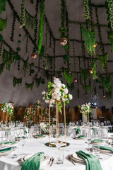 Obraz premium flower arrangements, empty glasses, plates with green napkins on a table.