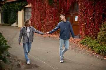 Young Cute Female Hugs Boyfriend. In Autumn Outdoor. Lovers Walking in Park. Attractive Funny Couple. Lovestory in Forest. Man and Woman. Cute Lovers in the Park. Family Concept. Happy Couple.