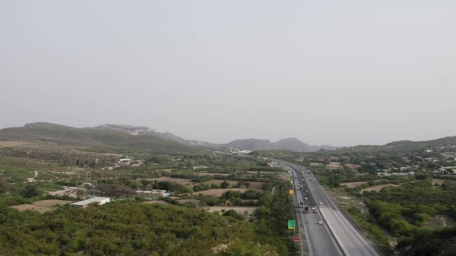 M2 motorway with vehicles cutting through hilly terrain near Kallar Kahar. Punjab, Pakistan