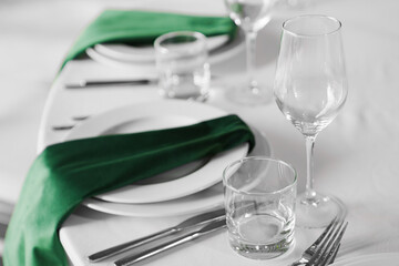 Empty glasses, plates with green napkins on a served festive table.
