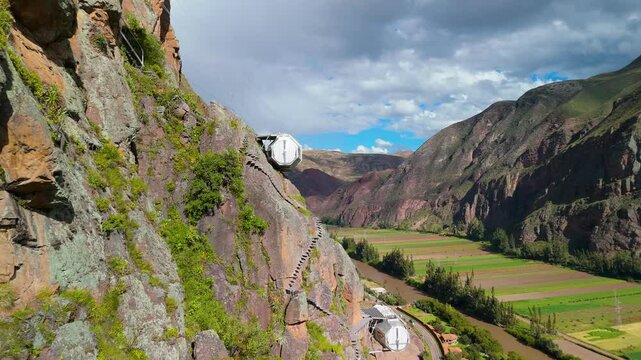 Steep stone and metal stairs ascend a dramatic cliff face, providing access to the transparent glass pods of Skylodge Adventure Suites suspended high above Peru's Sacred Valley.