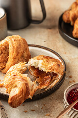 Delicious fresh croissants on ceramic plate close up and a cup of coffee, broken croissant with sweet feeling. Morning meal and breakfast concept